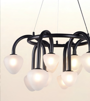 Modern multi-light chandelier with a matte black curved metal frame and frosted white glass shades, shown illuminated against a plain light background.