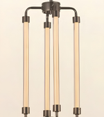 A modern three-light linear chandelier with a dark gunmetal finish and warm glowing frosted glass tubes, shown against a solid cream background.