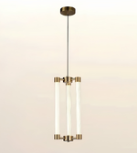 A modern three-light linear pendant chandelier with clear glass cylindrical tubes and brushed brass hardware, suspended from a round ceiling canopy against a light beige background.
