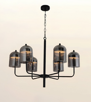 A modern six-light chandelier with a matte black metal frame and smoked glass bell shades, shown against a plain light beige background.