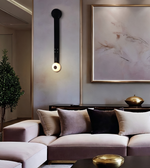 A modern living room setting featuring a plush mauve-pink sectional sofa with beige, taupe, and black velvet pillows, styled with a matching ottoman, a gold coffee table, and a large framed abstract art print on a textured gray wall.