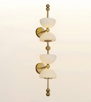 A modern wall-mounted light fixture with three tiers of frosted white glass shades and polished brass/gold-toned metal hardware, shown against a plain off-white background.