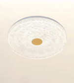 A round ceiling light fixture with a textured, frosted white glass or acrylic outer ring and a central gold-toned circular element, shown against a plain light background.