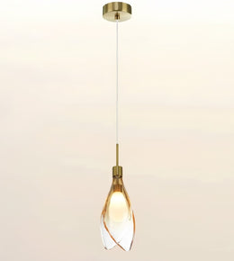 A modern single pendant light with a brushed brass ceiling canopy, cord, and cap, featuring a clear glass shade with twisted spiral edges that glow warm yellow from the light bulb inside.