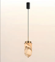 A modern pendant light with a black cylindrical ceiling canopy, a thin black cord, and a warm-toned marble-look glass shade with gold-toned metal accents, shown against a soft beige gradient background.