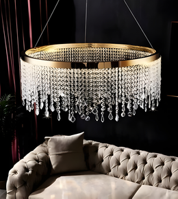 Luxury chandelier with crystal accents hanging above a sofa in a dimly lit room.