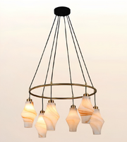 Modern circular ring chandelier  on white background featuring multiple marble-effect glass pendant lights with brushed brass accents and warm ambient illumination.