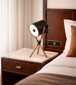 Industrial-style tripod table lamp placed on bedside table in contemporary bedroom interior