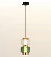 A modern multi-light pendant ceiling fixture with a black canopy and cord, featuring two stacked faceted glass shades—one clear textured and one green textured—separated by gold-toned metal rings, shown against a plain light background.