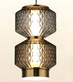 A modern two-tier pendant light fixture with textured, diamond-patterned smoked glass shades and polished brass-toned metal accents, shown illuminated against a plain light background.