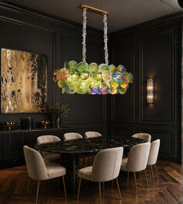 Luxury linear chandelier with handcrafted multicolour art glass discs suspended above a modern dining table.