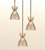 Three pendant light fixtures with tapered mosaic glass shades in a champagne-gold tone, suspended by black cords against a soft beige gradient background.