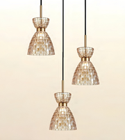 Three pendant light fixtures with tapered mosaic glass shades in a champagne-gold tone, suspended by black cords against a soft beige gradient background.