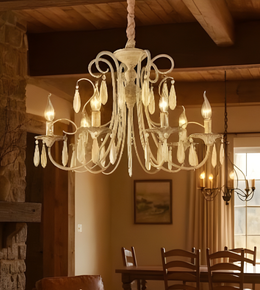 Chandelier hanging in a warmly lit room with wooden furniture and stone wall.
