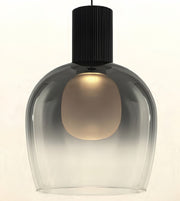 A modern pendant light with a ribbed black metal top cap and a clear glass shade that reveals a warm glowing frosted inner bulb, set against a plain off-white background.