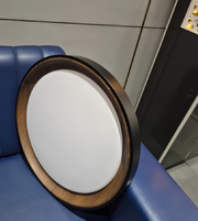Round light fixture with wooden frame on a blue surface