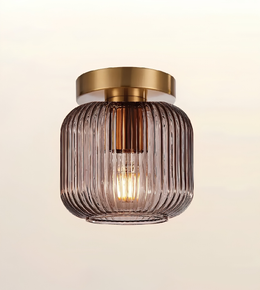 A modern semi-flush mount ceiling light fixture featuring a ribbed, translucent smoky purple glass shade and a brushed brass gold ceiling canopy, shown against a plain off-white background.