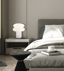 A modern bedroom scene featuring a white mushroom-shaped table lamp on a gray stone nightstand next to a bed with white bedding and a gray headboard.