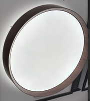 Round mirror with wooden frame on a white wall
