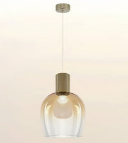A modern pendant light with a clear ribbed glass shade and a brushed brass cylindrical neck, suspended by a thin cord from a matching ceiling canopy against a warm off-white background.