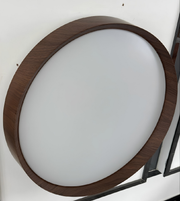 Round ceiling light fixture with wooden frame on a white wall