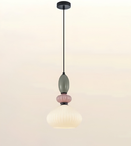 A modern pendant light fixture with a black ceiling canopy and cord, featuring a sculptural design with a muted sage green bulb, a pink ribbed accent, and a ribbed white glass shade.