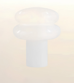 A frosted white plastic or silicone cap with a rounded, mushroom-like top and a cylindrical base, shown against a soft, light beige gradient background.