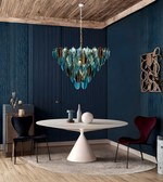 Modern dining room with a blue glass chandelier, round white table, and dark blue walls.