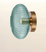 A modern wall-mounted light fixture featuring a ribbed, oval-shaped translucent glass shade in a light teal-blue color, paired with a brushed gold metal wall mount.