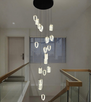 Modern chandelier hanging in a staircase area with a neutral color scheme.