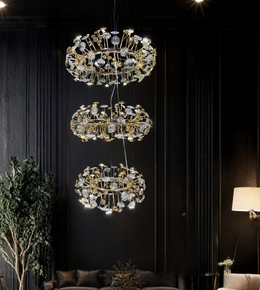 Three ornate chandeliers hanging in a dark room with a couch and lamp.