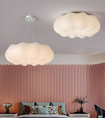 Two cloud-shaped ceiling lights in a bedroom with a pink paneled wall.