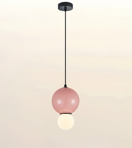 A modern pendant light with a matte black ceiling canopy and cord, featuring a large dusty pink glass globe shade with a smaller white globe bulb hanging below, set against a soft beige gradient background.