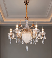 Detailed view of the chandelier's curved gold-tone arm and clear crystal-style hanging ornaments.