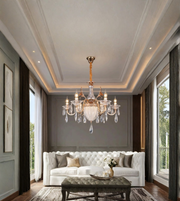 Gold crystal chandelier with clear decorative drops and candle-style lights displayed above an elegant white sofa in a luxury living room.