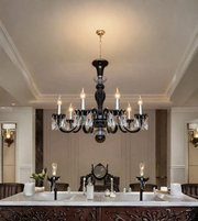  Black crystal chandelier with illuminated candle-style bulbs and hanging crystal accents above a formal dining table in an elegant interior.