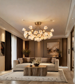  Luxury gold floral chandelier with white flower-shaped shades illuminating a contemporary living room with neutral furnishings.