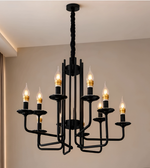 Close-up of a black contemporary chandelier featuring curved metal-look arms, gold-tone bulb-holder accents, and illuminated flame-shaped bulbs.