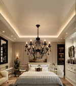 Black crystal chandelier with ornate curved arms and candle-style lights suspended above a bed in an elegant neutral-toned bedroom.