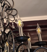 Detailed view of the black metal chandelier arms, candle-shaped filament bulbs, and decorative hanging crystal accents.