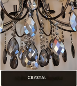 Close-up of a luxury chandelier with faceted hanging crystal drops and a dark metal frame.