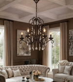 Vintage black metal crystal chandelier with ornate scrollwork and candle-style lights displayed in an elegant living room.