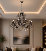 Black decorative crystal chandelier suspended above a luxury living room with neutral furnishings, framed wall panelling, and warm ambient lighting.