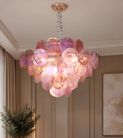 Close-up of a luxury pink shell disc chandelier featuring layered translucent pink and peach decorative discs with a rose-gold ceiling fitting.