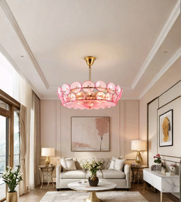 Luxury pink disc chandelier with a gold-tone frame suspended above a contemporary living room with neutral furnishings and warm ambient lighting.