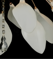 Close-up of a modern chandelier with glossy white teardrop-shaped glass shades and rose gold metal arms against a black background.