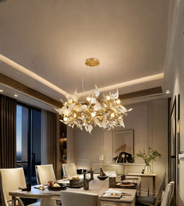A modern chandelier with white sculptural leaf-like branches and gold-toned metal supports, hanging over a dining table in a contemporary dining room.