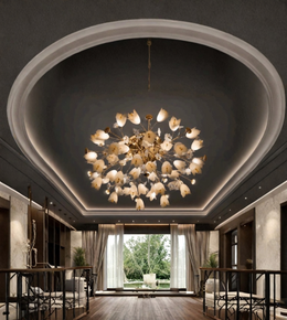 A large multi-light chandelier with glowing flower-shaped bulbs hangs from a decorative oval recessed ceiling in a modern dining room with dark wood floors and light walls.