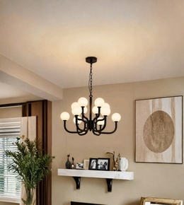 A multi-light chandelier with black metal arms and glowing white globe bulbs hanging in a warm, modern living room setting.