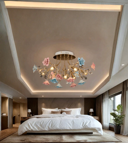 A decorative ceiling light fixture with hanging flower-shaped glass shades in pink, blue, and white, mounted on a gold-toned branch structure in a modern bedroom with a high vaulted ceiling.